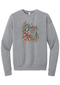 A Savior Is Born To Us crewneck sweatshirt in Athletic Heather, featuring watercolor evergreen and holly with a red ribbon bow, the words A Savior is born to us, and Isaiah 9:6