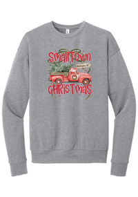Personalized Small Town Christmas crewneck sweatshirt in Athletic Heather, featuring Santa in a vintage red pickup truck hauling a Christmas tree past a personalized town road sign, with red Small Town Christmas lettering