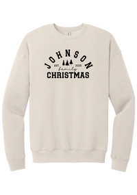 Personalized Family Christmas crewneck sweatshirt in Heather Dust, featuring an arched family name over pine trees with EST. year and family Christmas lettering