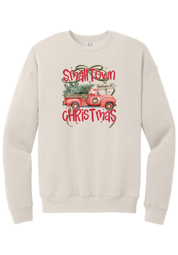 Personalized Small Town Christmas crewneck sweatshirt in Heather Dust, featuring Santa in a vintage red pickup truck hauling a Christmas tree past a personalized town road sign, with red Small Town Christmas lettering
