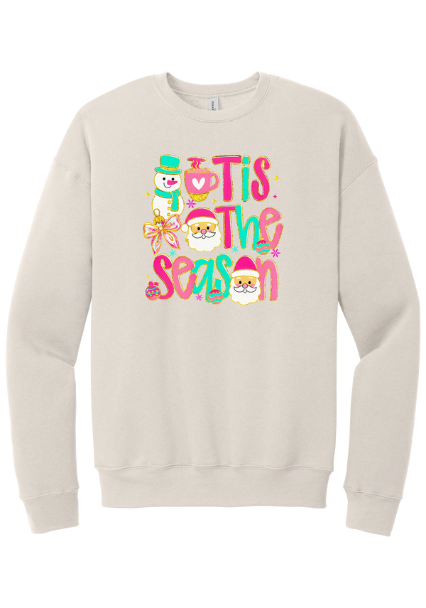 Tis the Season Snowman crewneck sweatshirt in Heather Dust, featuring pink and teal TIS THE SEASON letters with a snowman, a cocoa mug, and Santas