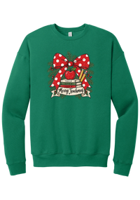 Merry Teachmas crewneck sweatshirt in Kelly Green, featuring a red polka dot bow over a stack of books reading Teach, Inspire, Change with an apple, pencils, evergreen, and a Merry Teachmas banner