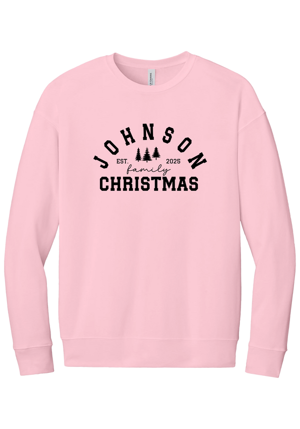 Personalized Family Christmas crewneck sweatshirt in Pink, featuring an arched family name over pine trees with EST. year and family Christmas lettering