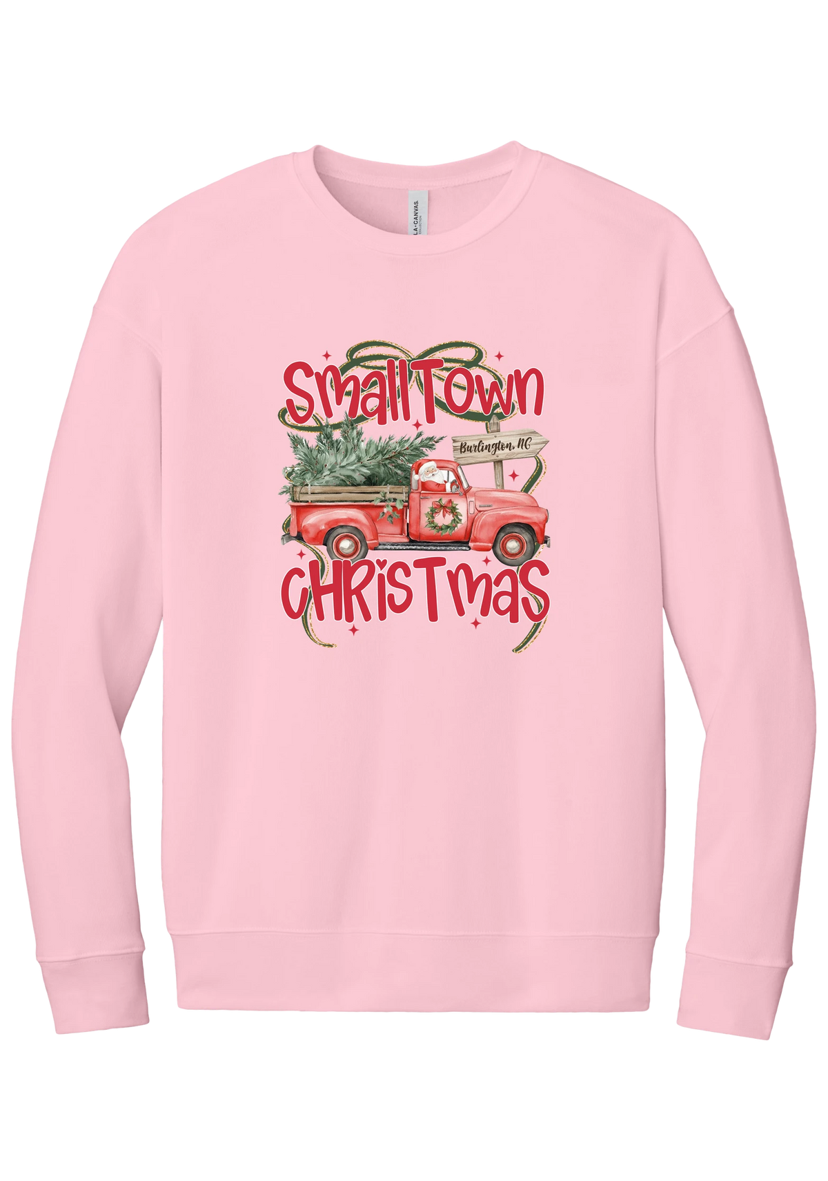 Personalized Small Town Christmas crewneck sweatshirt in Pink, featuring Santa in a vintage red pickup truck hauling a Christmas tree past a personalized town road sign, with red Small Town Christmas lettering