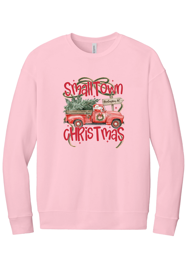 Personalized Small Town Christmas crewneck sweatshirt in Pink, featuring Santa in a vintage red pickup truck hauling a Christmas tree past a personalized town road sign, with red Small Town Christmas lettering