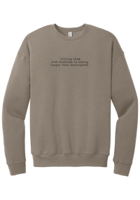 Killing Them With Kindness crewneck sweatshirt in Tan, featuring Killing them with kindness is taking longer than anticipated in distressed black typewriter letters