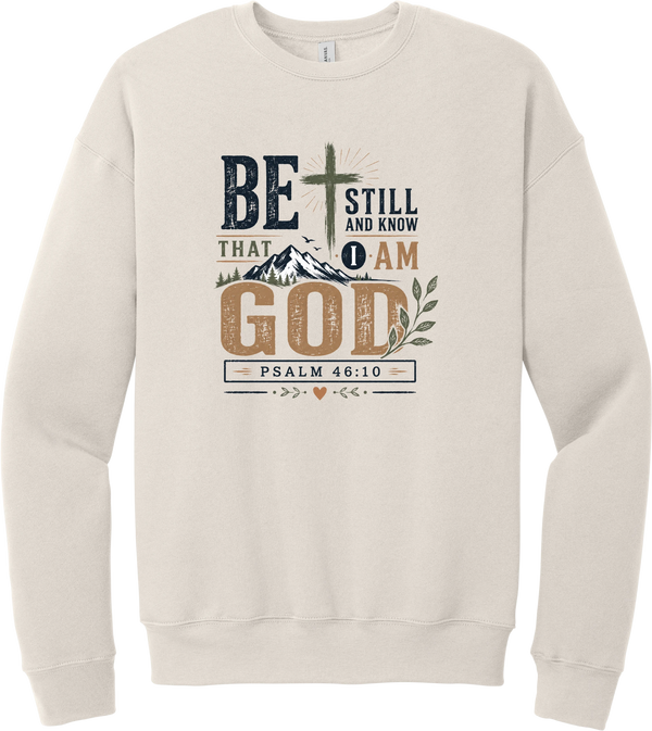 Be Still and Know crewneck sweatshirt in Heather Dust, featuring Be Still and Know That I Am God lettering with a cross over mountains and Psalm 46:10