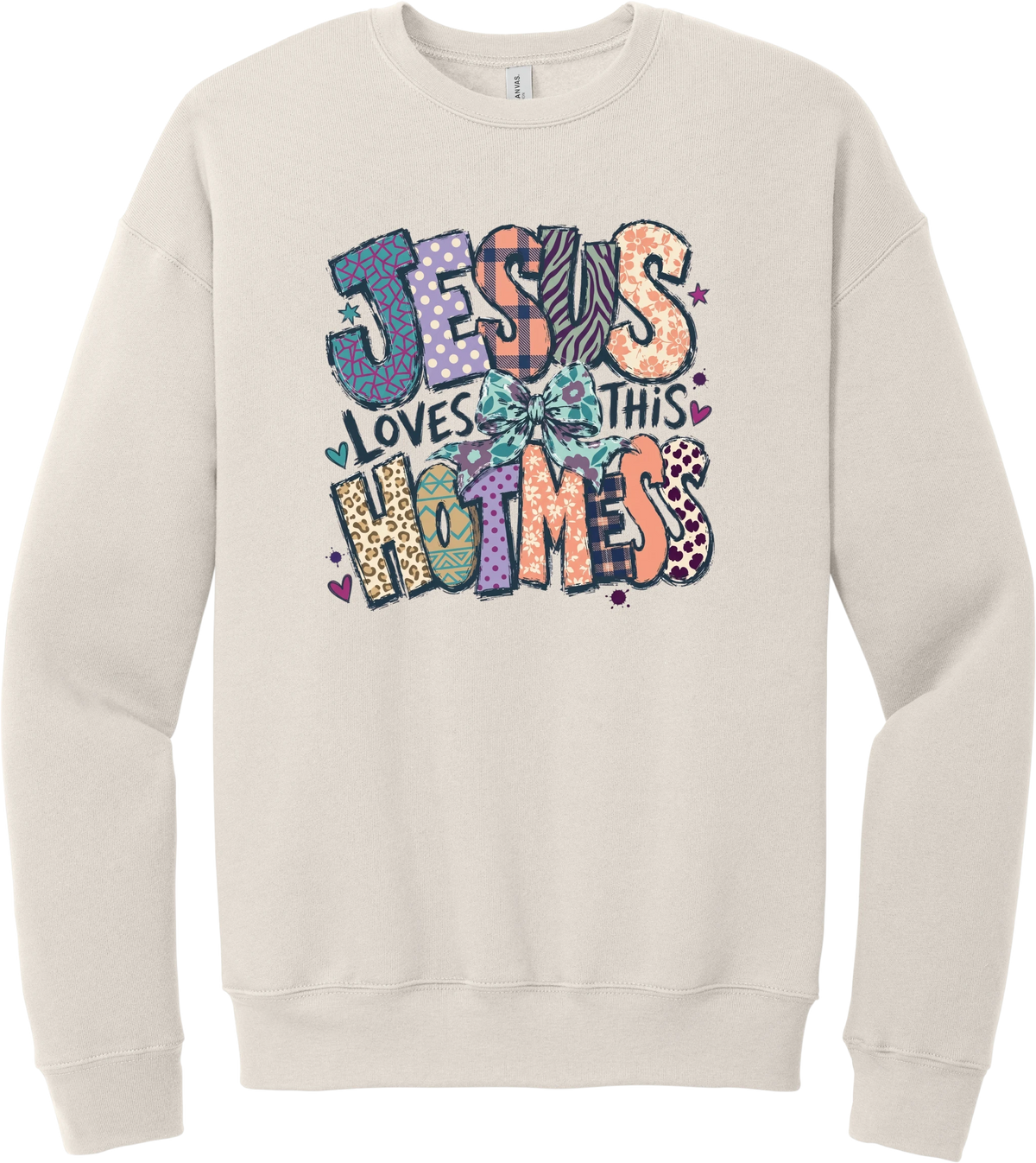 Jesus Loves This Hot Mess crewneck sweatshirt in Heather Dust, featuring patchwork Jesus Loves This Hot Mess lettering in leopard, plaid, polka dot, and zebra prints with a bow and hearts