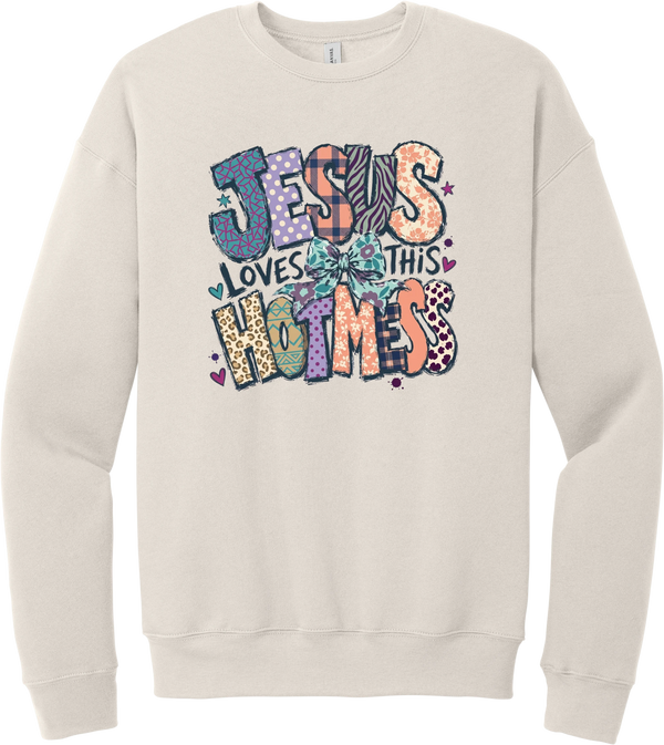 Jesus Loves This Hot Mess crewneck sweatshirt in Heather Dust, featuring patchwork Jesus Loves This Hot Mess lettering in leopard, plaid, polka dot, and zebra prints with a bow and hearts