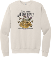 Words Like Honey crewneck sweatshirt in Heather Dust, featuring a dripping honeycomb with bees and wildflowers under Kind Words Are Like Honey lettering and Proverbs 16:24