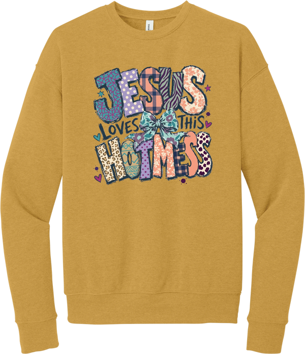 Jesus Loves This Hot Mess crewneck sweatshirt in Heather Mustard, featuring patchwork Jesus Loves This Hot Mess lettering in leopard, plaid, polka dot, and zebra prints with a bow and hearts