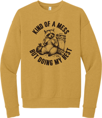Kind of a Mess But Doing My Best crewneck sweatshirt in Heather Mustard, featuring a raccoon sitting beside a trash can with Kind of a mess but doing my best