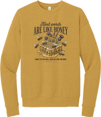 Words Like Honey crewneck sweatshirt in Heather Mustard, featuring a dripping honeycomb with bees and wildflowers under Kind Words Are Like Honey lettering and Proverbs 16:24