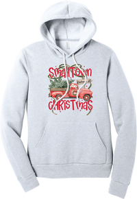 Personalized Small Town Christmas hoodie in Ash, featuring Santa in a vintage red pickup truck hauling a Christmas tree past a personalized town road sign, with red Small Town Christmas lettering