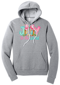 Joy to the World Nativity hoodie in Athletic Heather, featuring painted JOY letters framing a nativity scene with a pink bow and To The World script