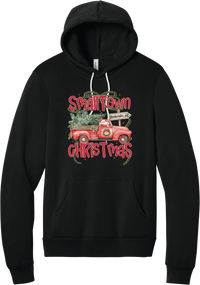 Personalized Small Town Christmas hoodie in Black, featuring Santa in a vintage red pickup truck hauling a Christmas tree past a personalized town road sign, with red Small Town Christmas lettering