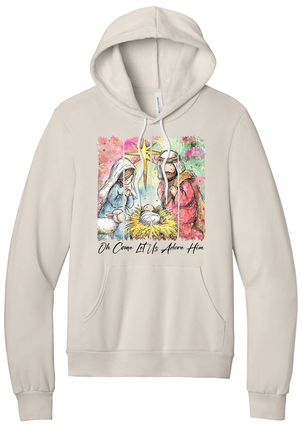 Adore Him Painted Nativity hoodie in Heather Dust, featuring a watercolor nativity of Mary, Joseph, and baby Jesus under a star with Oh Come Let Us Adore Him script