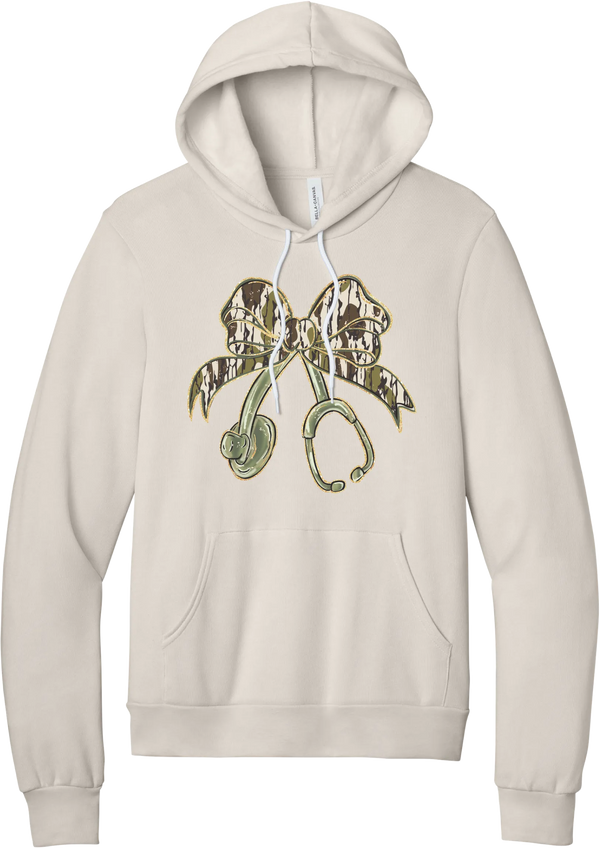 Camo Bow Stethoscope hoodie in Heather Dust, featuring a glittery camo print coquette bow tied to a sage green stethoscope