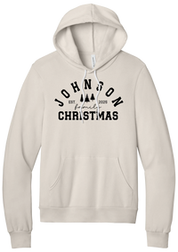 Personalized Family Christmas hoodie in Heather Dust, featuring an arched family name over pine trees with EST. year and family Christmas lettering