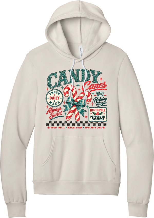 Fresh Candy Canes hoodie in Heather Dust, featuring vintage candy shop lettering with two striped candy canes tied in a green bow, a North Pole Peppermint Goodness sign, and a checkerboard stripe