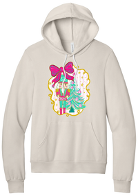Nutcracker Bow hoodie in Heather Dust, featuring a teal and pink nutcracker beside a tinsel tree under a big hot pink bow