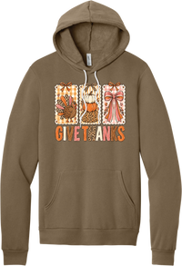 Give Thanks Coquette hoodie in Vintage Brown, featuring three bow-topped stamp panels with a turkey, stacked pumpkins, and a pink bow above Give Thanks in patchwork letters