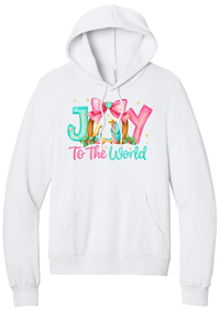Joy to the World Nativity hoodie in White, featuring painted JOY letters framing a nativity scene with a pink bow and To The World script