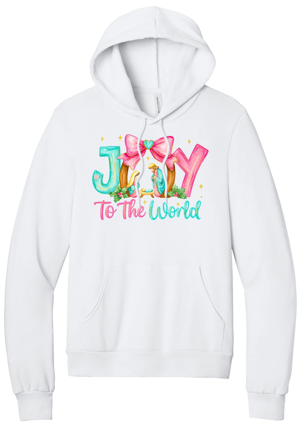 Joy to the World Nativity hoodie in White, featuring painted JOY letters framing a nativity scene with a pink bow and To The World script