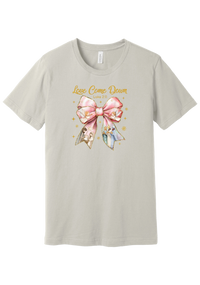 Love Came Down Nativity Bow tee in Dust, featuring a blush satin bow with painted nativity scenes under gold Love Came Down script and Luke 2:11
