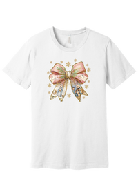 Nativity Bow tee in White, featuring a blush satin bow with painted nativity scenes in its ribbons and gold snowflakes